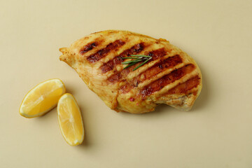 Grilled chicken meat and lemon on beige background