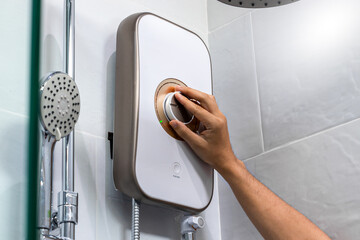 Hand person with water heater control panel in white bathroom