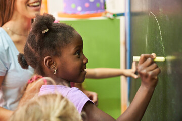 African girl paints with chalk on the blackboard