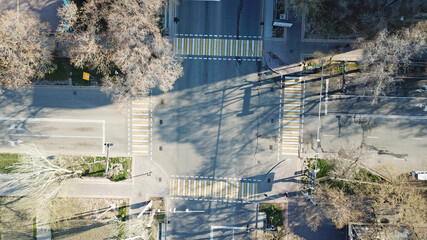 Fototapeta na wymiar Top view of a road junction in the city of Almaty. The vehicle is waiting for the traffic light signal and is moving in its own direction. Cars, buses, and people move through the intersection.