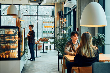 Friends having a chat, talking together, drinking coffee, sitting in a cafe. Young man and woman...