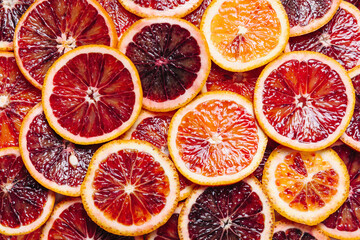 Bright colorful background of fresh ripe sliced blood oranges. Close up, flat lay.