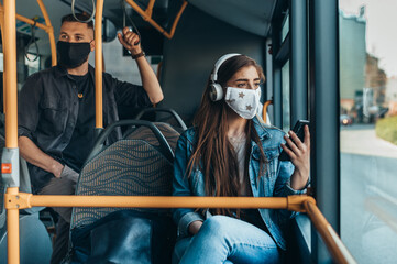 Obraz na płótnie Canvas Woman wearing protective mask and using a smartphone while riding a bus