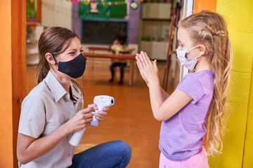 Girls and kindergarten teachers disinfect their hands
