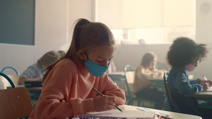 Student in protective mask studying at school during corona virus pandemic