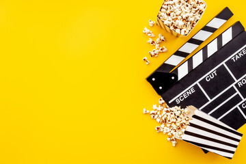 Popcorn with clapperboard and movie film reel. Cinema background