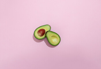 Avocado divided in half with a pink background. Flat lay concept.
