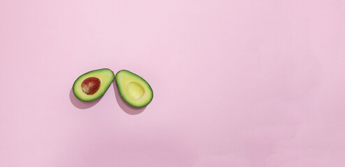 Avocado divided in half with a pink background. Flat lay concept.