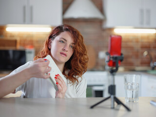 Technology and blogging concept. Redhair woman recording video concent for her blog at home