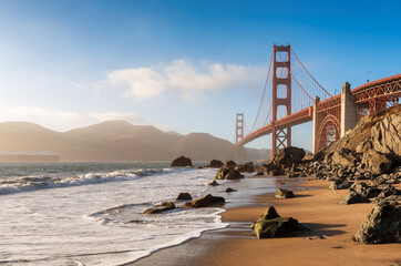 Golden Gate Bridge view from California beach, ocean wave, sand and rocks in Marshall’s Beach,...