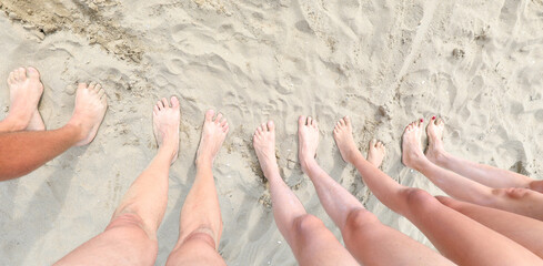 legs with bare feet of a large family of 5 on the sand during the summer holidays