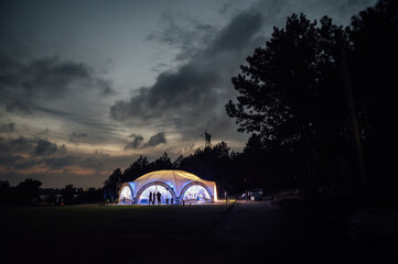 Large wedding tent in the open area for receiving guests. Evening photo with a beautiful sunset