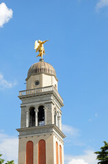 Obraz premium golden statue of a large angel above the bell tower of the castle in the city of Udine in northern Italy