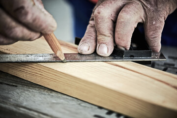 Senior carpenter taking measurement in his workshop