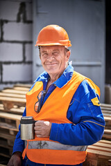 Smiling construction worker having coffee break on construction site