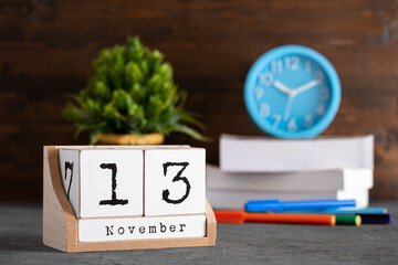 November 13th. November 13 wooden cube calendar with blur objects on background.