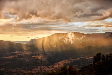 Aerial, dramatic view on illuminated rain over slopes of Bale mountains covered in Harenna forest,...