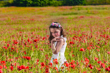 Girl walking on poppy field at dusk