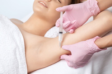 Aesthetic cosmetologist makes lipolytic injections to burn fat on the arm and body of a woman. Female aesthetic cosmetology in a beauty salon.Cosmetology concept.