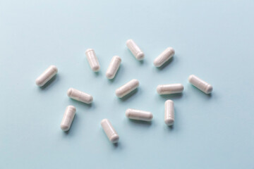 White pills on a blank colored background. Medicines, vitamins, treatment and pharmacology concept