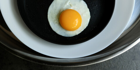 a fried egg in a pan, in 2 plate