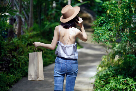 Stylish woman holding paper bag and using mobile phone. 