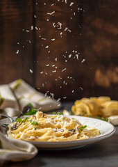 Pasta fettuccine with mushrooms and fried chicken ham in creamy cheese sauce on a light wooden background - obrazy, fototapety, plakaty