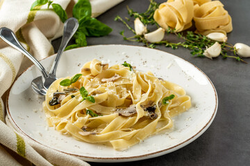 Pasta fettuccine with mushrooms and fried chicken ham in creamy cheese sauce on a light wooden...