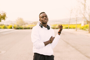 Young african American black man with afro hair dancing in the street wearing a white sweatshirt,...