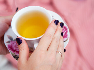 A cup of tea in the hands of a woman. Time to relax. Tea break.