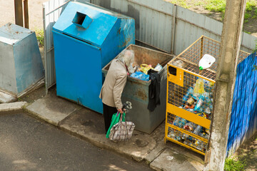 Beggar man rummages in the trash can