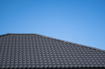 Fototapeta na wymiar Brown corrugated metal profile roof installed on a modern house. The roof of corrugated sheet. Roofing of metal profile wavy shape. Modern roof made of metal. Metal roofing.