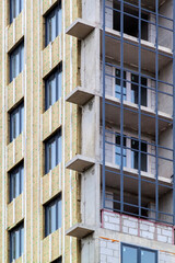 Installation of external wall thermal insulation with rock wool. Exterior passive house wall heat insulation with mineral wool. Insulation facade of multistory residential building. Energy efficiency