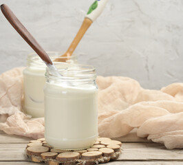 homemade yogurt in a glass transparent jar on a wooden table