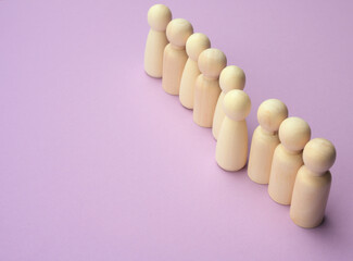 wooden men stand in a row, one figurine sticking out in front.