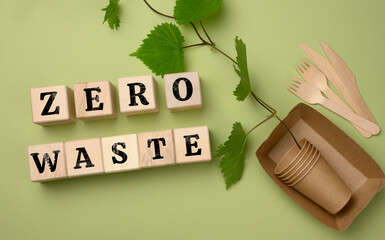 wooden cubes with an inscription zero waste and paper plates and disposable cups. The concept of...