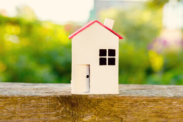 Obraz na płótnie Canvas Miniature white toy model house in wooden background near green backdrop. Eco Village, abstract environmental background. Real estate mortgage property insurance dream home ecology concept.