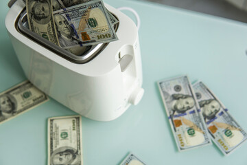 US Hundred dollar bills burning in the toaster. US dollars roasting in toaster. Financial concept.