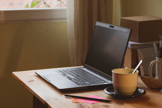 The home office, an example of a space for teleworking from home, where you can see a laptop and a cup of coffee or hot tea, early in the morning, in Madrid, Spain. Work-life balance.