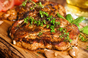 Fried pork steak on a wooden board to serve with vegetables and a mug of beer.