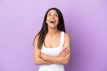 Young caucasian woman isolated on purple background looking up and with surprised expression