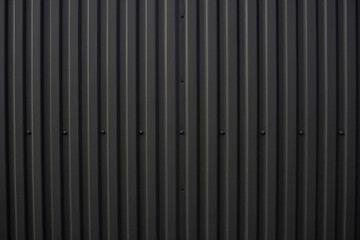Black corrugated iron sheet used as a facade of a warehouse or factory. Texture of a seamless...
