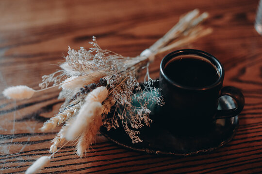 A Cup Of Black Coffee And Dried Flowers On A Wooden Table. View From Above