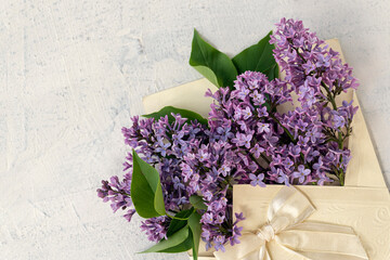purple flowers in a beautiful envelope with a bow. Beautiful lilac flowers with copy space. Flat lay with spring blossom. spring or summer concept.