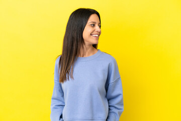 Young caucasian woman isolated on yellow background looking side