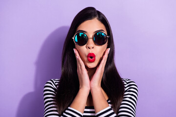 Photo of pretty shocked young woman dressed striped outfit dark glasses arms cheeks isolated violet color background