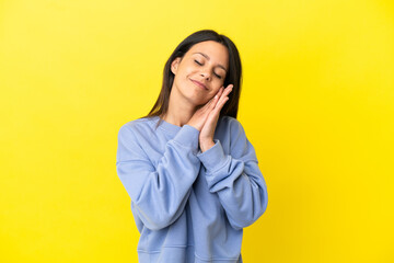 Young caucasian woman isolated on yellow background making sleep gesture in dorable expression