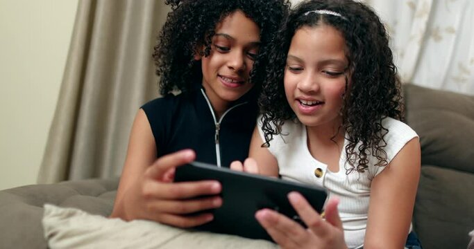 Two little girls using smartphone device at home. Preteen friends sharing smartphone screen