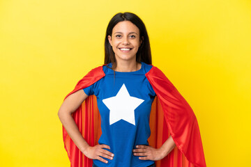 Woman isolated on yellow background in superhero costume posing with arms at hip and smiling © luismolinero