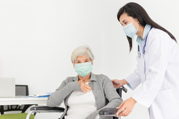 close up old asian patient, female doctor diagnosis and treatment old patient, patient cough and feeling chest pain, she sitting on wheelchair, they wear surgical mask, respiratory disease protection